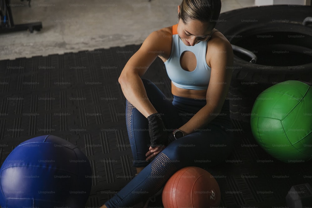 uma mulher sentada no chão ao lado de três bolas de exercício