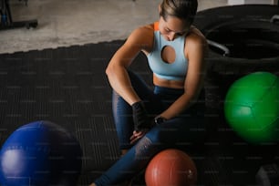 una donna seduta a terra accanto a tre palle da ginnastica