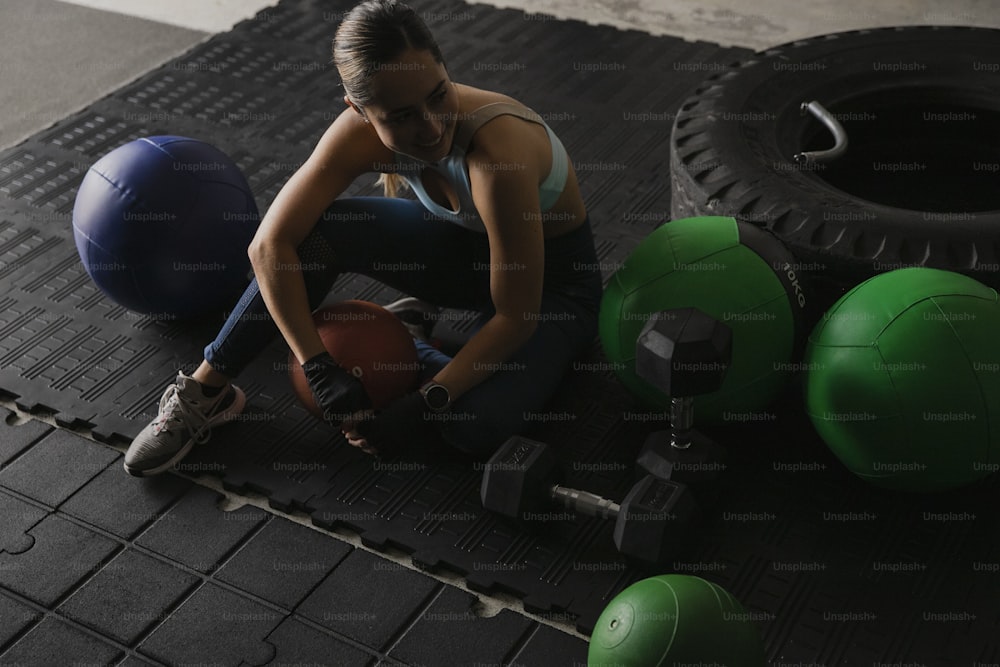 a woman sitting on a mat with a medicine ball