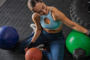 Una mujer sentada en el suelo junto a dos pelotas de ejercicio