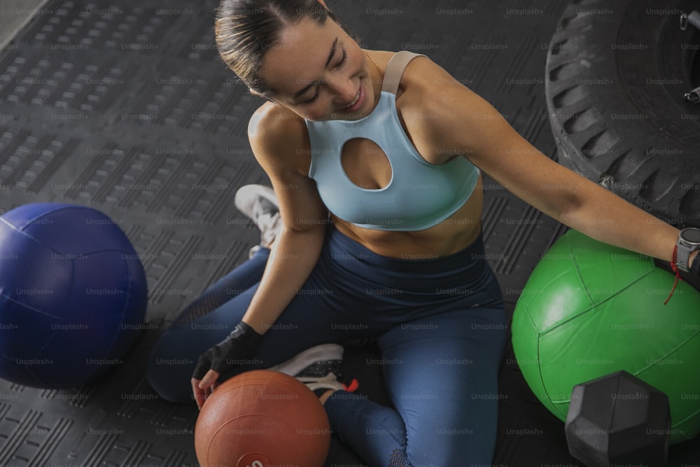 uma mulher sentada no chão ao lado de duas bolas de exercício