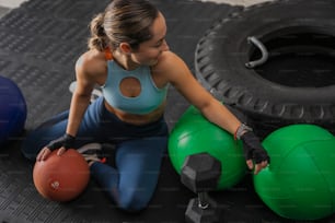 a woman sitting on the ground with some exercise balls