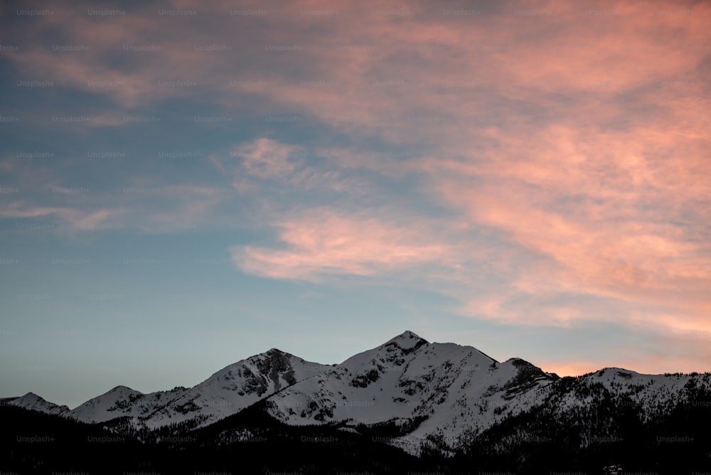 ピンク色の空を背景に雪に覆われた山