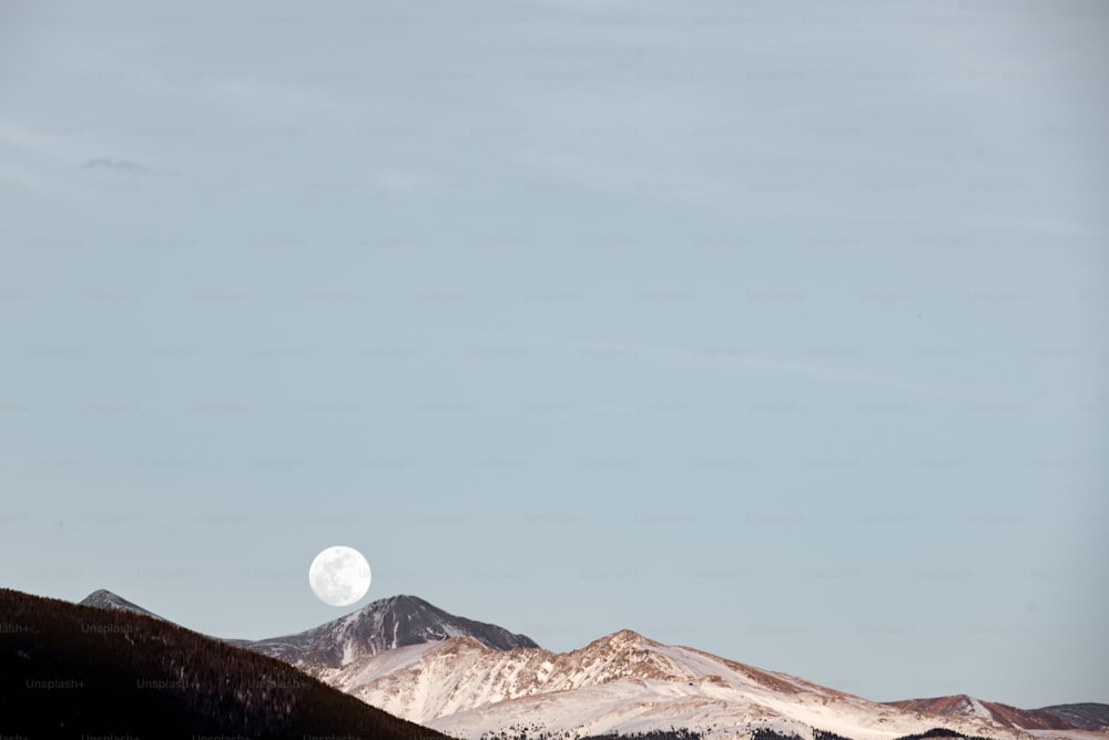 Une pleine lune se levant sur une chaîne de montagnes