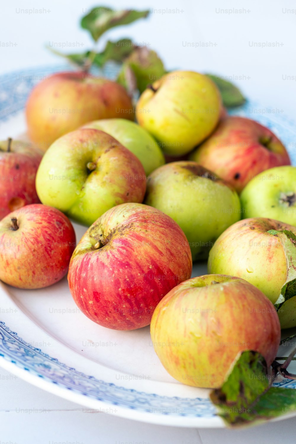 a white plate topped with lots of green and red apples