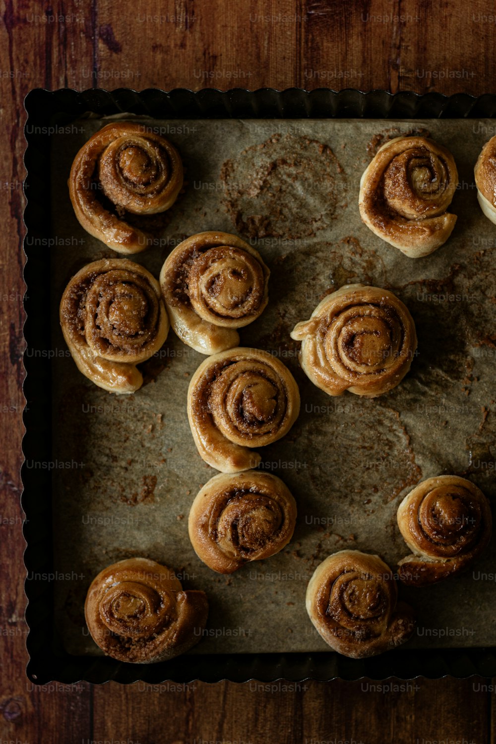 a baking tray filled with cinnamon rolls on top of a wooden table