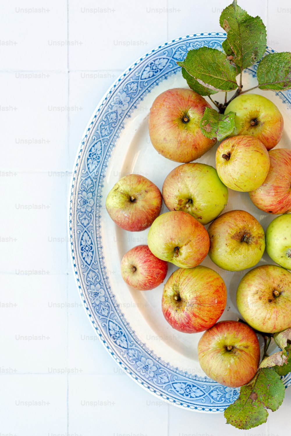 a blue and white plate topped with lots of apples