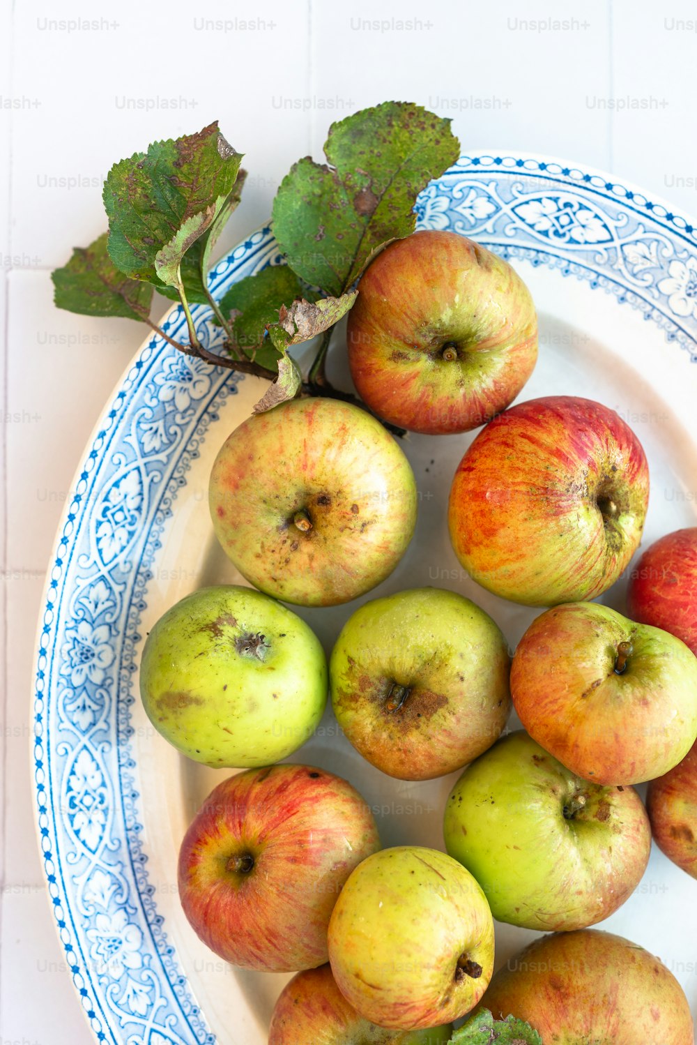 a white and blue plate topped with lots of apples