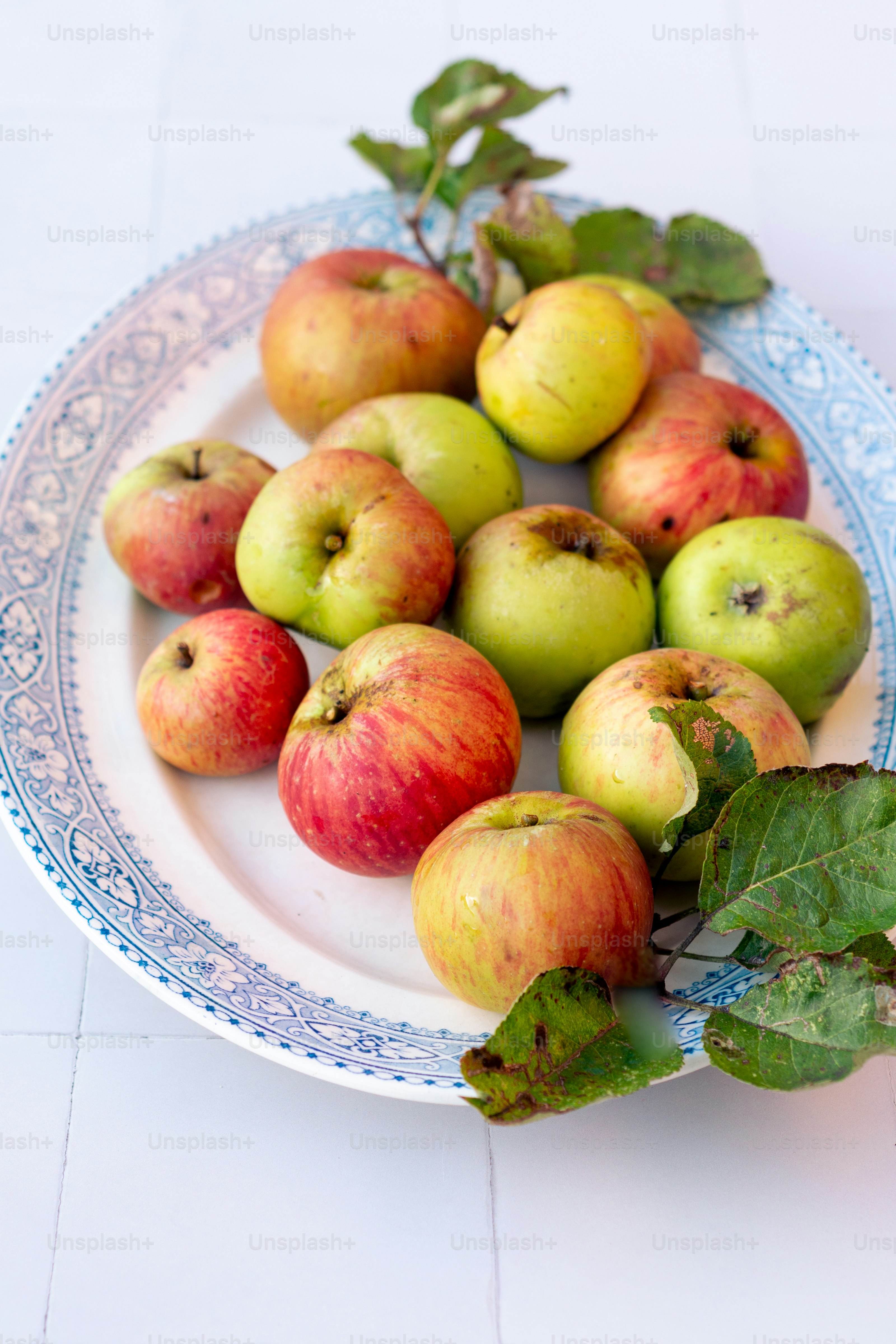 ein weißer Teller mit vielen grünen und roten Äpfeln