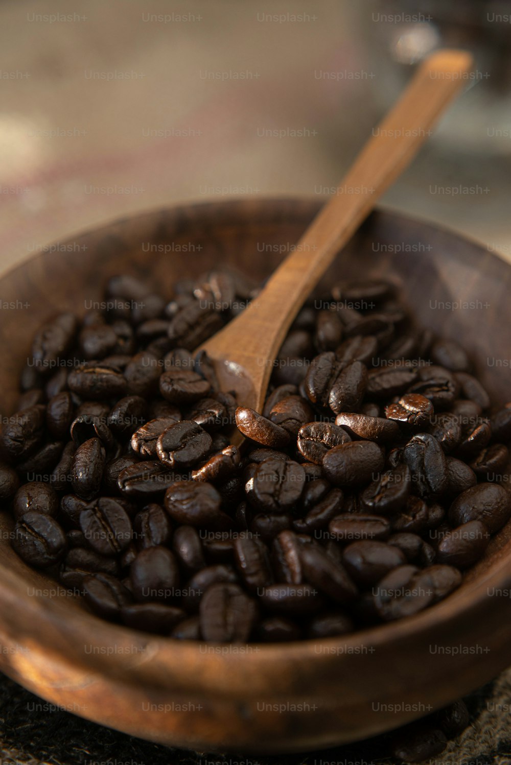 a wooden bowl filled with coffee beans and a wooden spoon