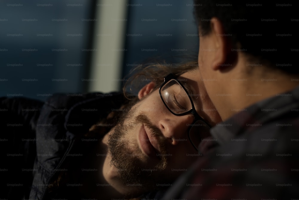 a man with glasses laying down next to another man