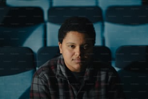 a man sitting in front of a row of blue chairs