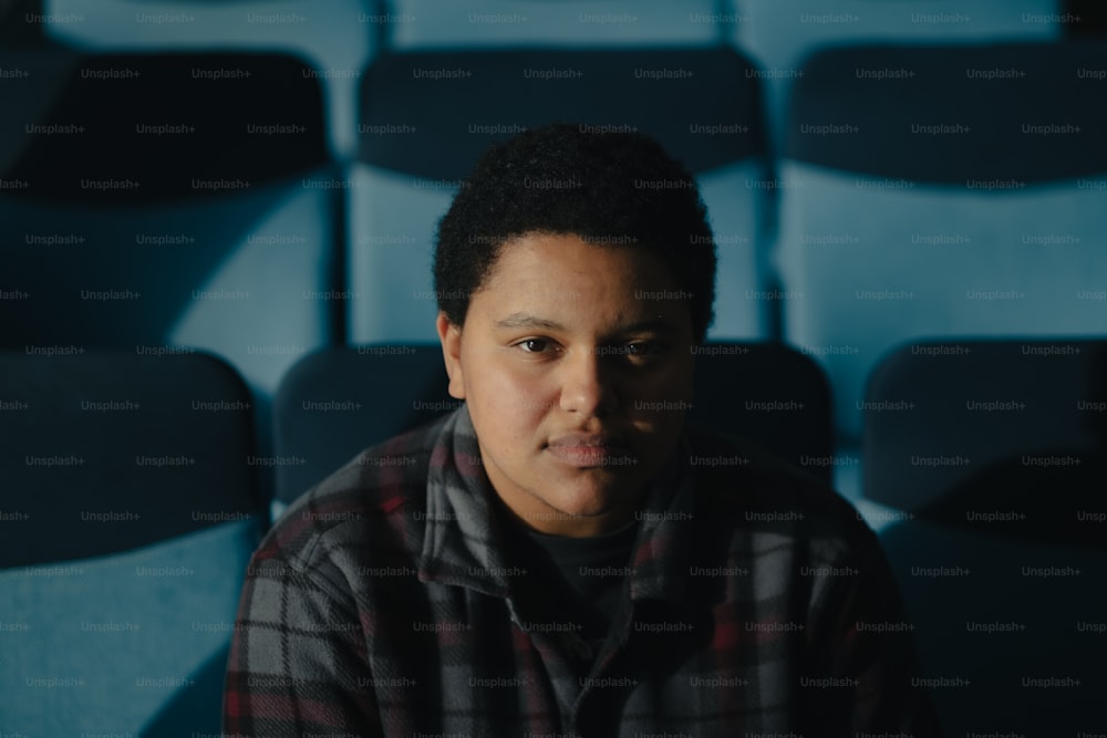 a man sitting in front of a row of blue chairs