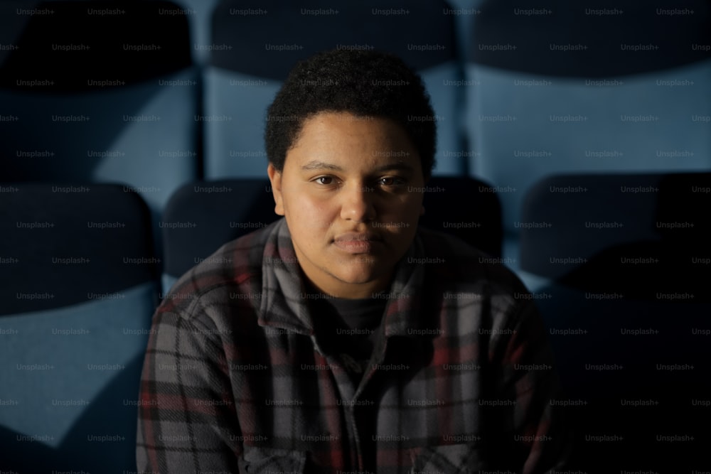 a man sitting in front of a row of blue chairs