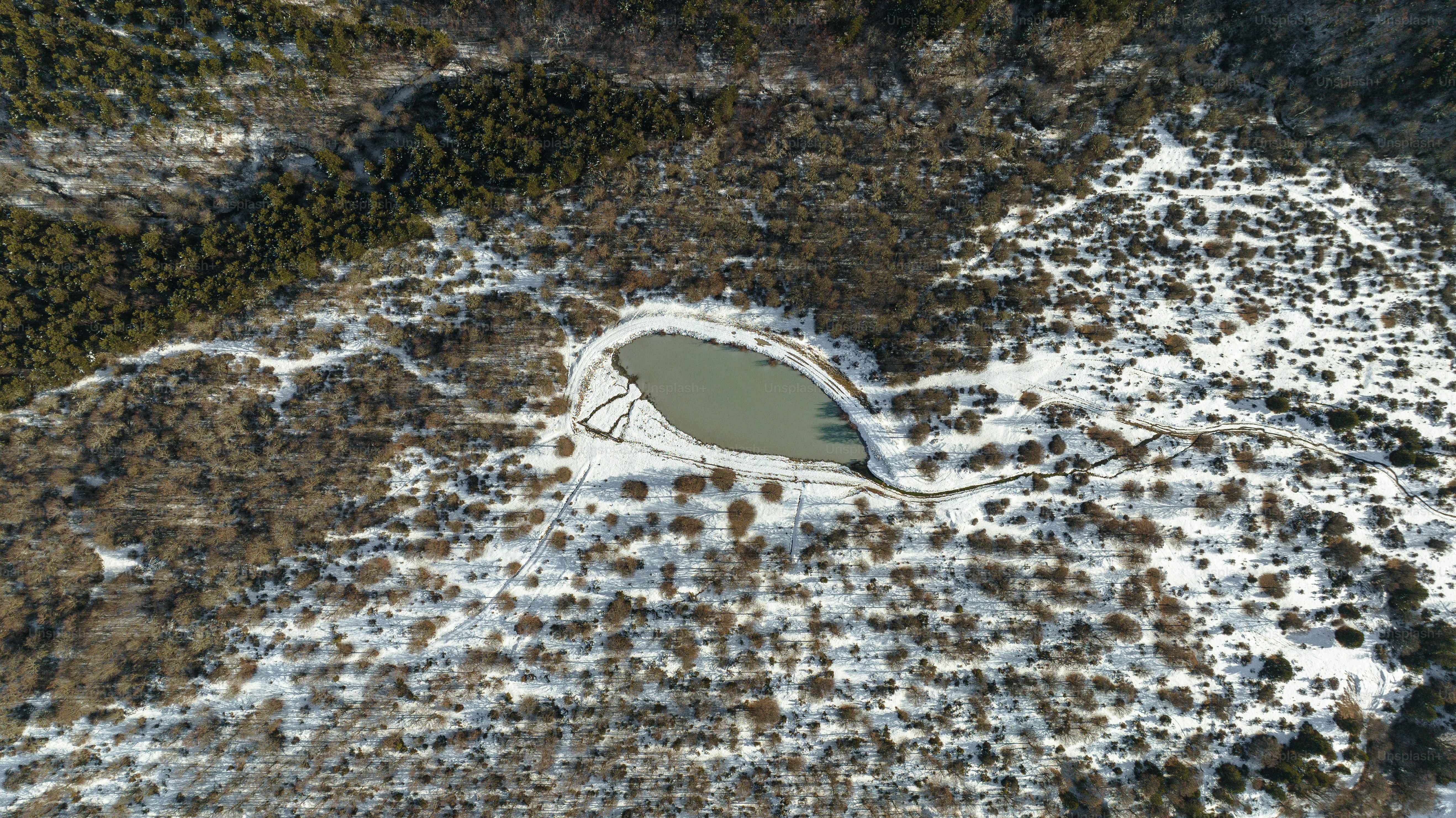 an aerial view of a lake surrounded by snow