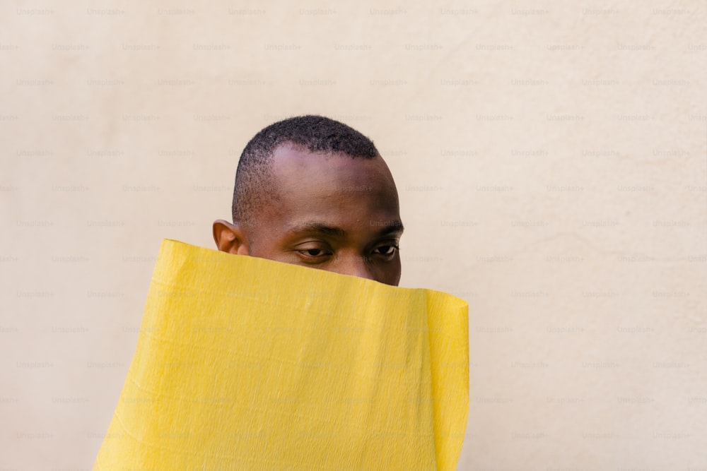 Un hombre escondiendo su rostro detrás de una tela amarilla