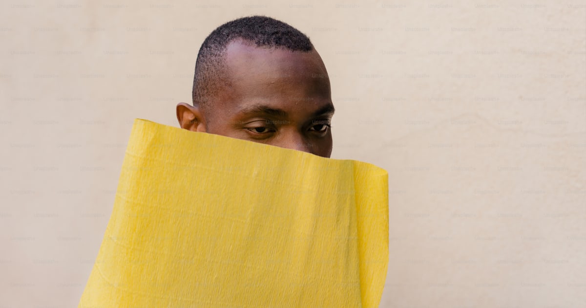 A man hiding his face behind a yellow cloth photo – Fashion Image on ...