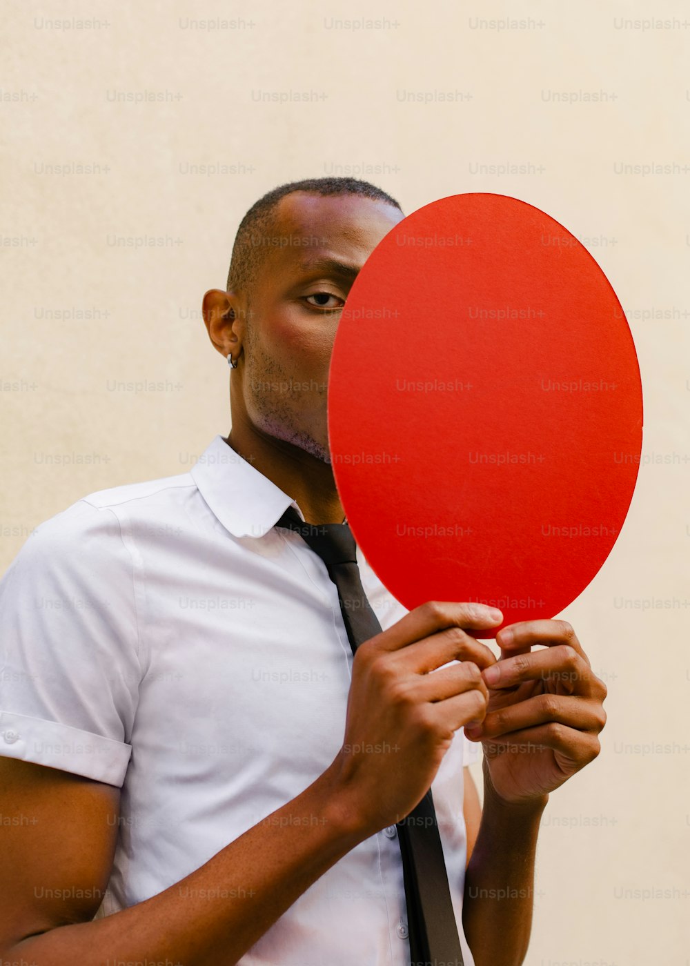 um homem segurando um balão vermelho na frente de seu rosto