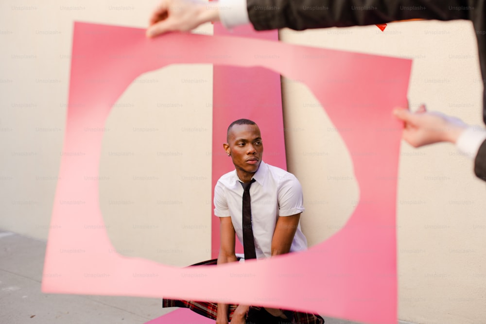 a man in a tie sitting on a pink piece of paper