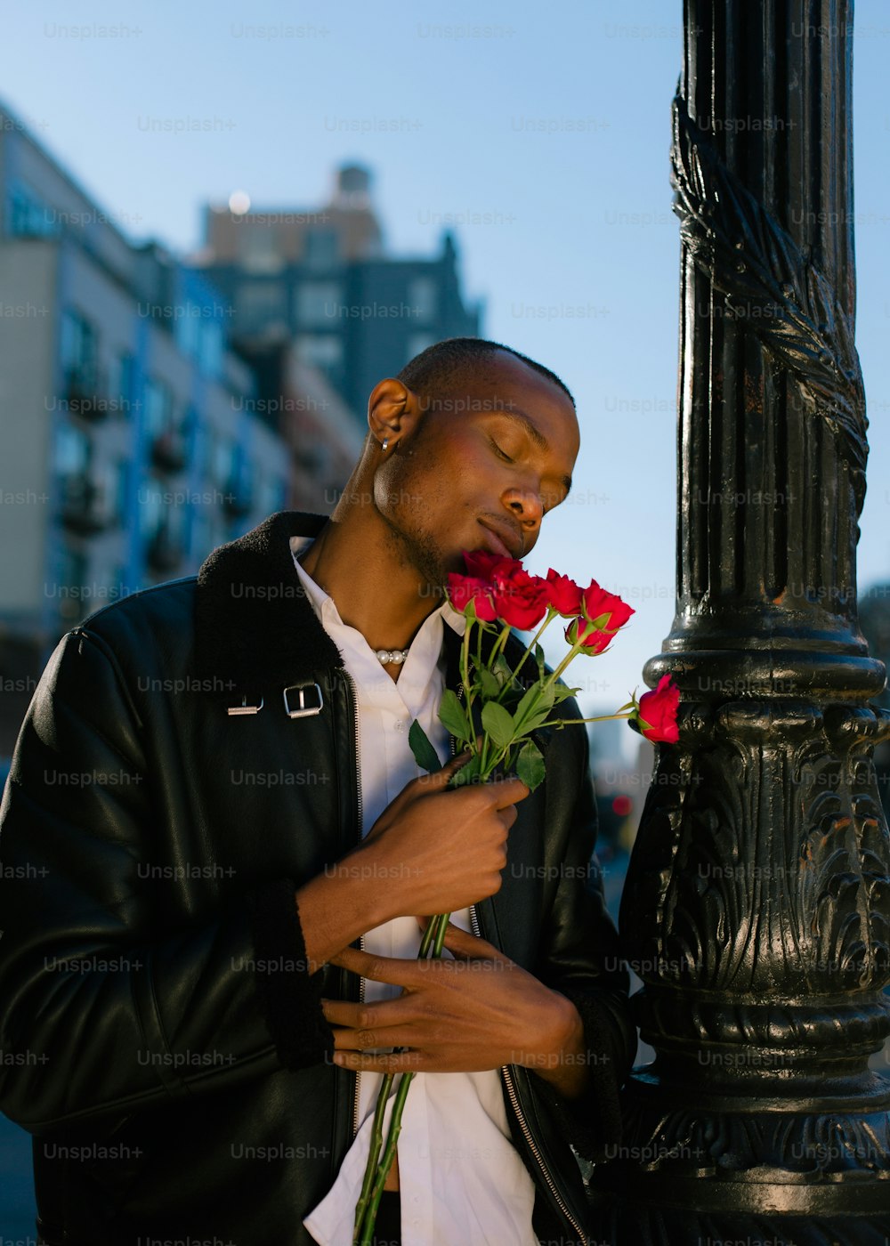 a man holding a bunch of flowers next to a pole