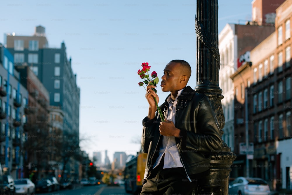 Un hombre parado en una esquina sosteniendo una flor