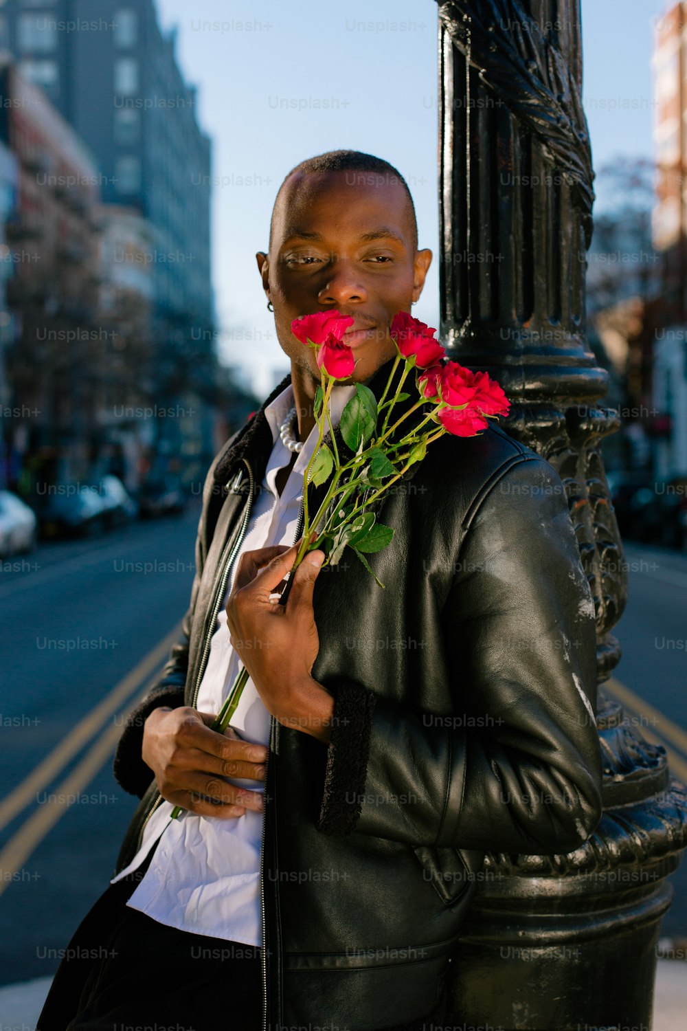 a man standing next to a pole holding a bunch of flowers