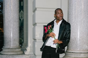Un homme en veste de cuir tenant un bouquet de fleurs
