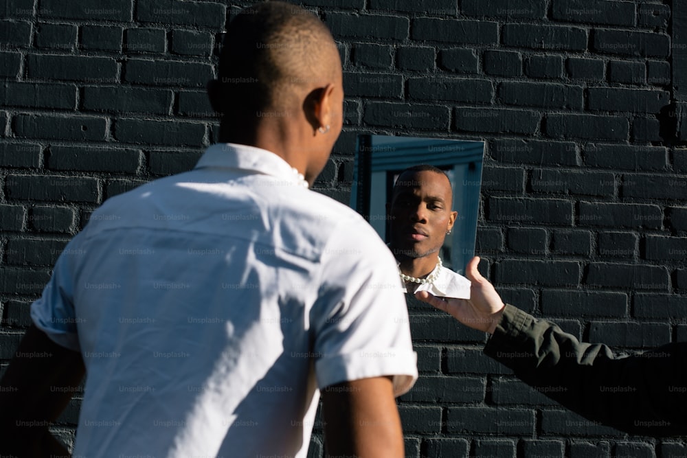 Un hombre parado frente a una pared de ladrillos hablando con otro hombre