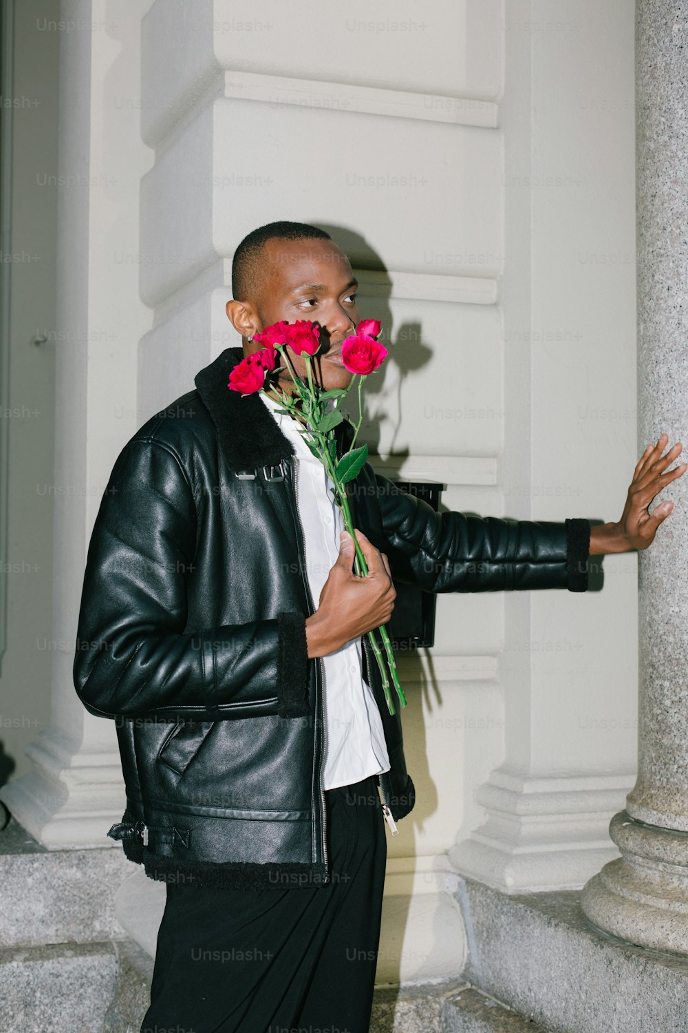 Un uomo in una giacca di pelle che tiene un mazzo di fiori