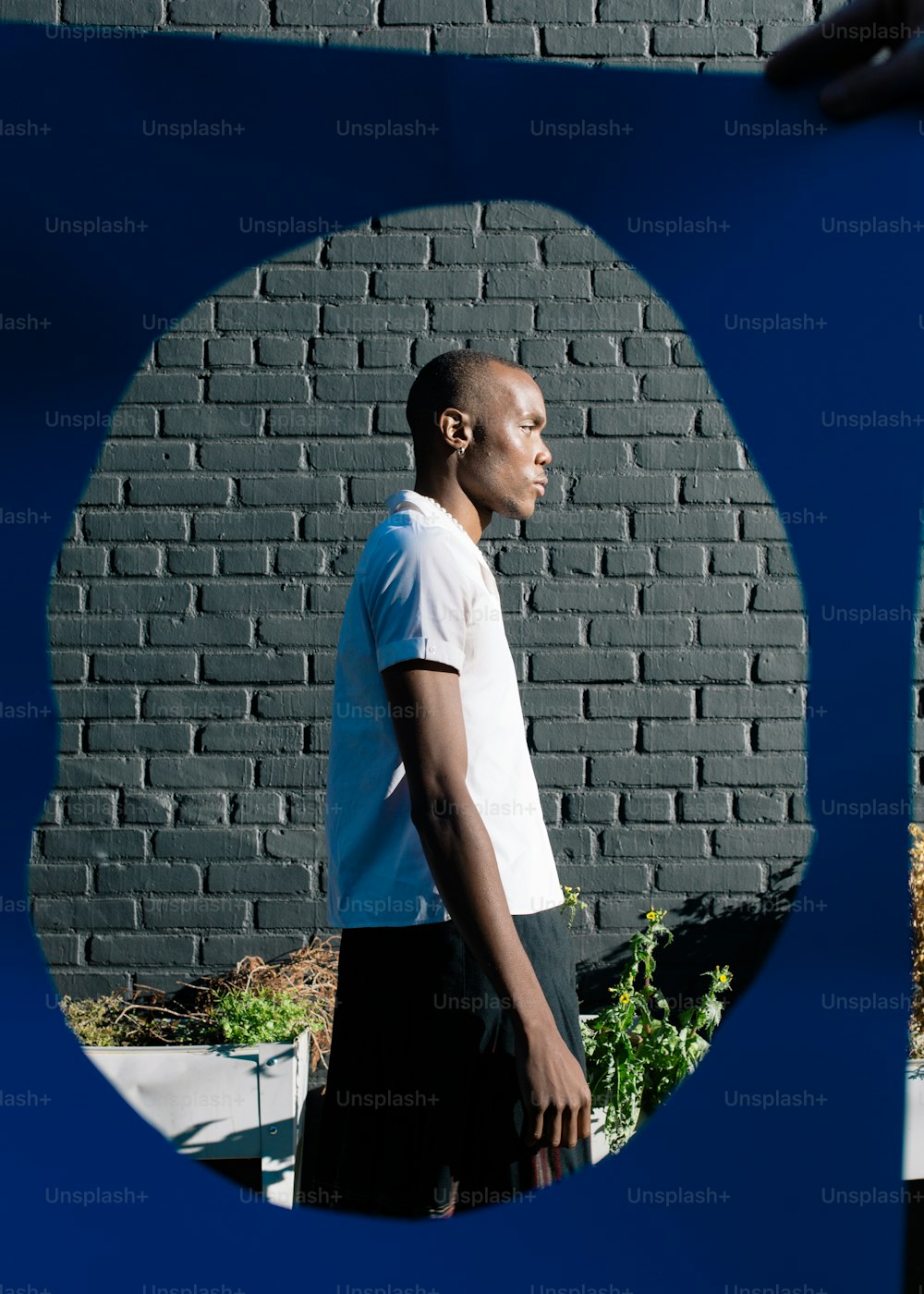 um homem em pé na frente de uma parede de tijolos