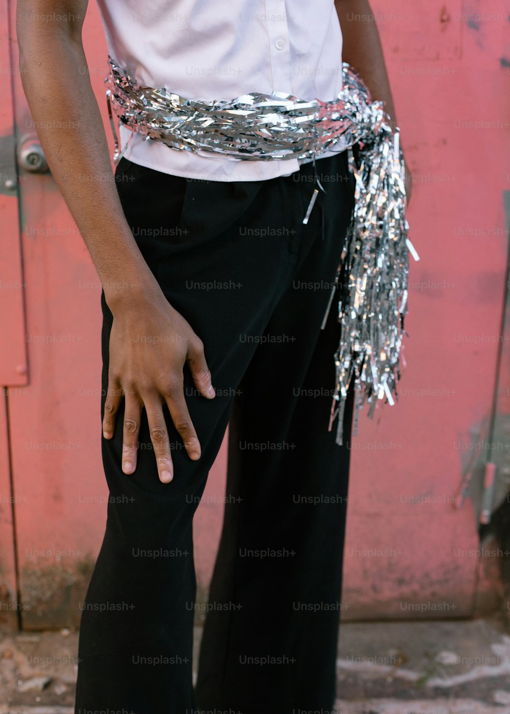 a person wearing a silver belt and a white shirt