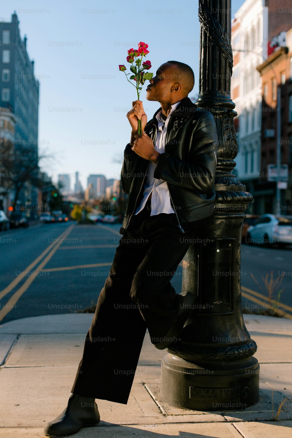 a man leaning on a pole with a flower in his hand