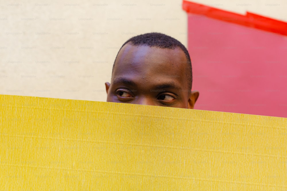 a man peeking over a yellow piece of paper