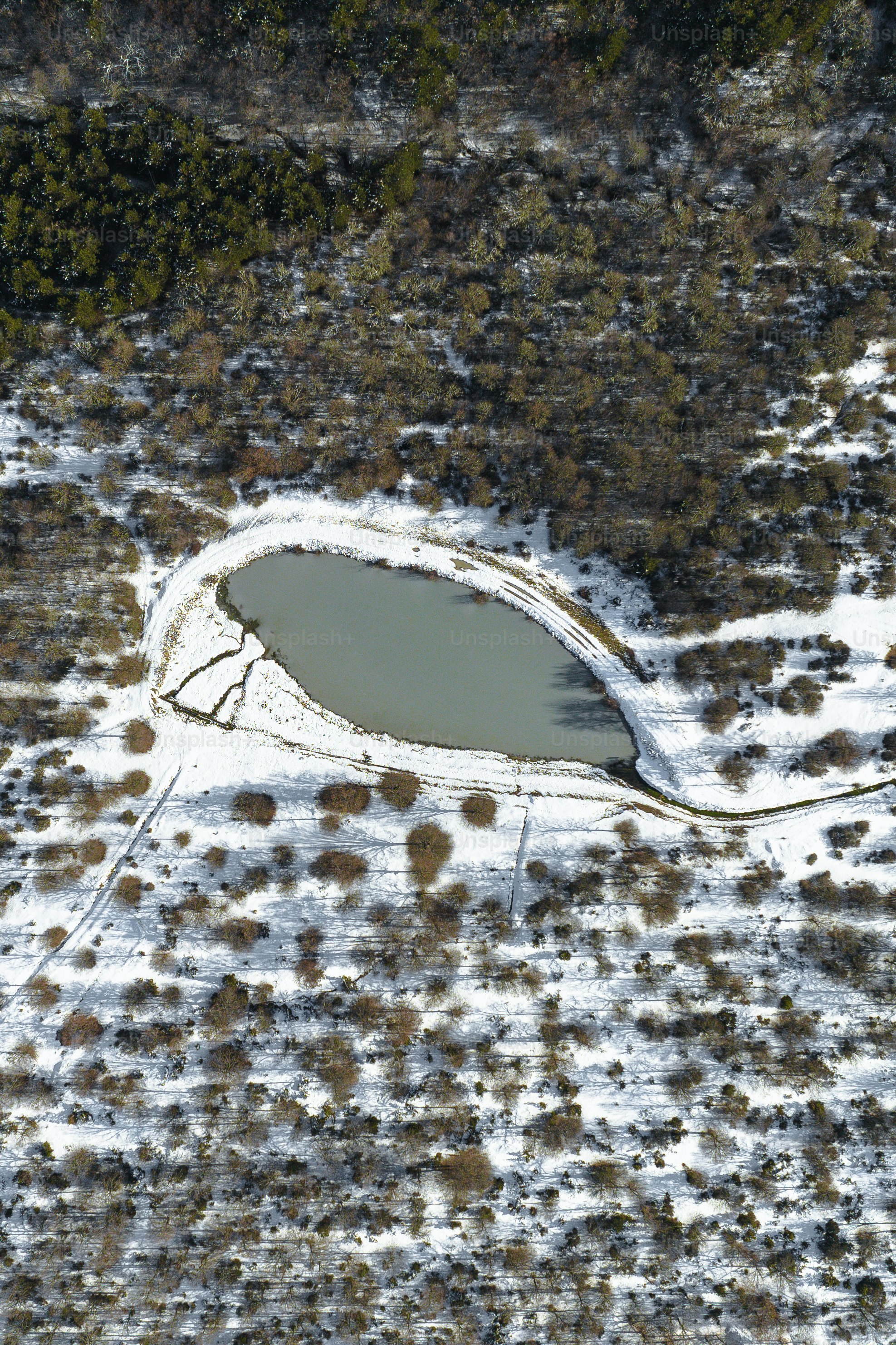 an aerial view of a snow covered field and lake