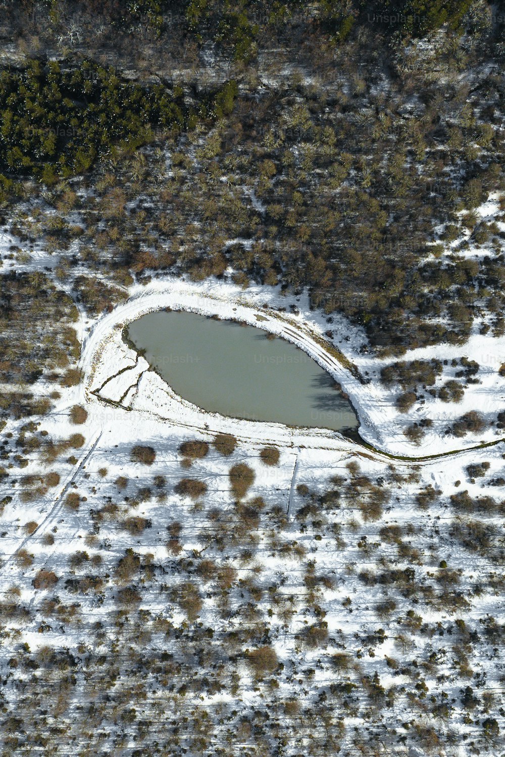 an aerial view of a snow covered field and lake