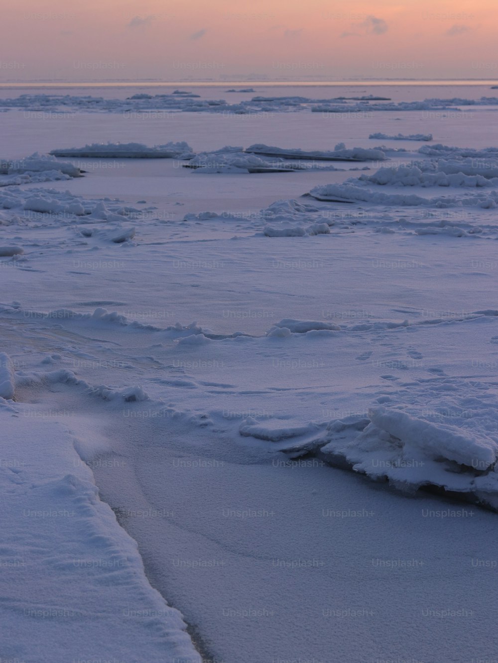 a snowy landscape with ice floes and a sunset in the background