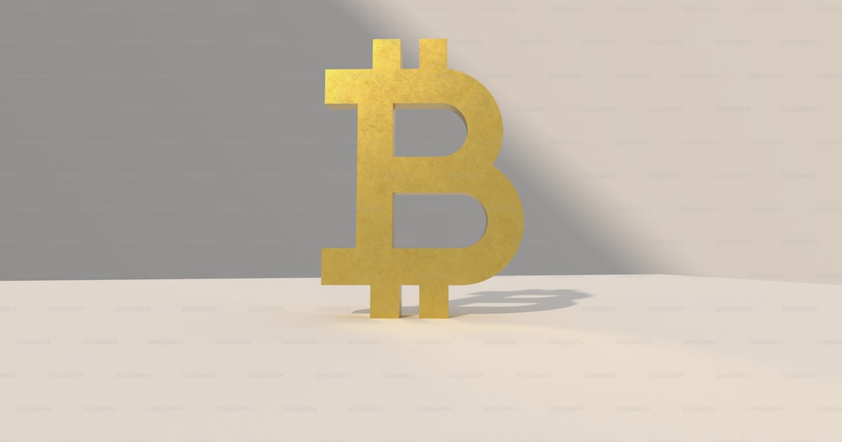 A yellow bit coin sitting on top of a table photo – Bitcoin Image on ...