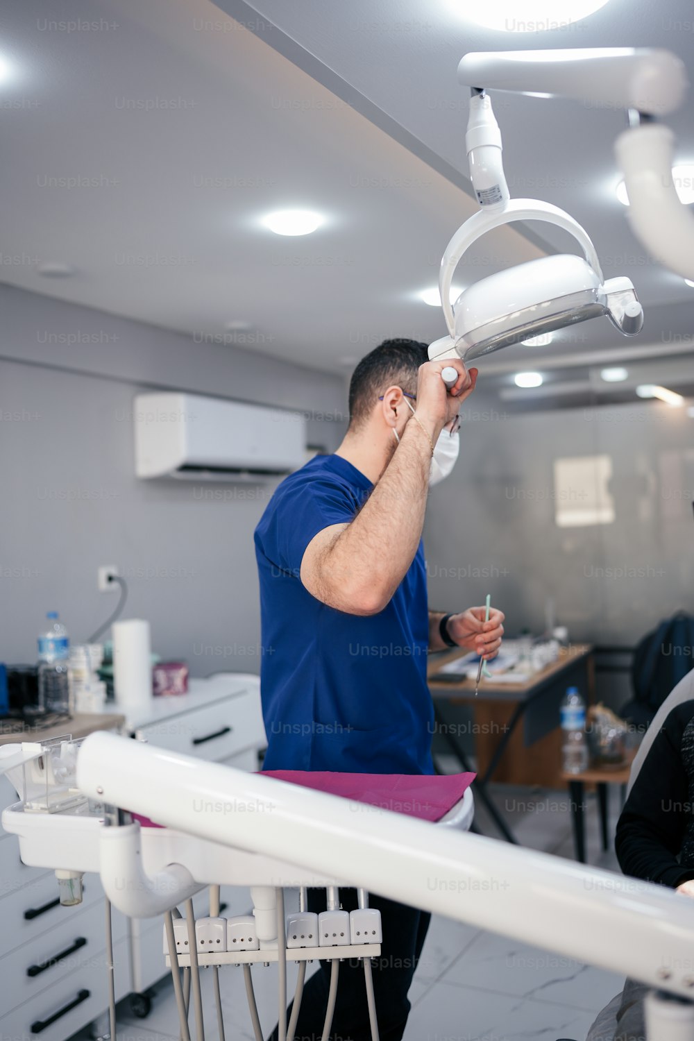 a man standing in a dentist's office holding a light above his head