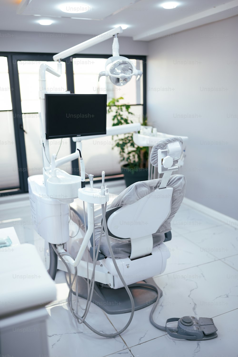 a dentist chair with a monitor and lights in a room