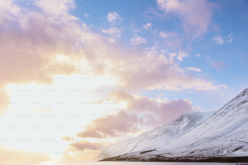 uma montanha coberta de neve sob um céu azul nublado