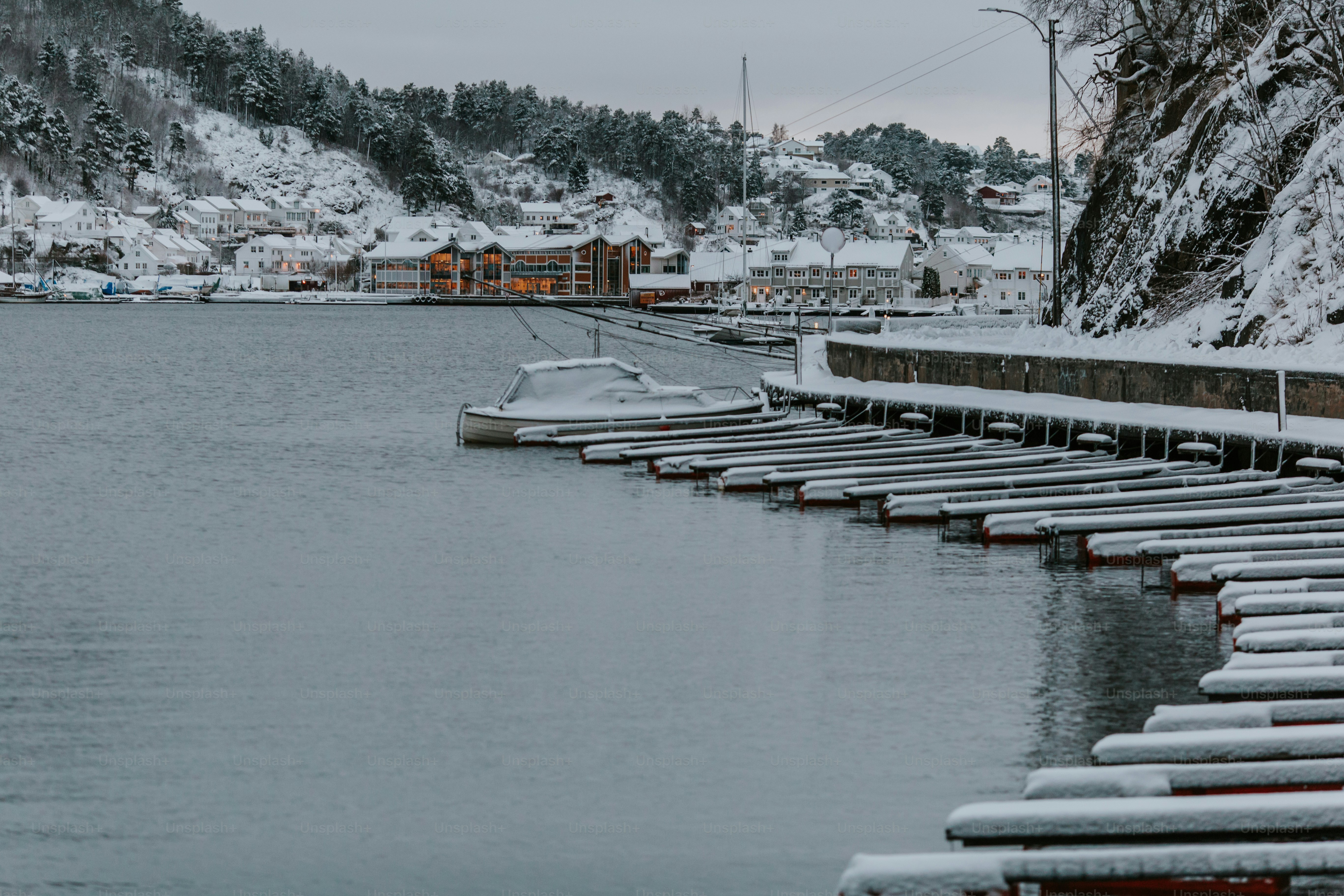 a row of boats sitting on top of a lake covered in snow