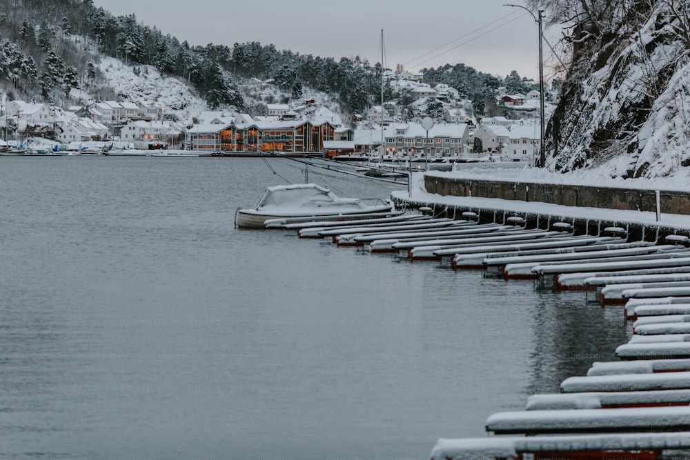 a row of boats sitting on top of a lake covered in snow