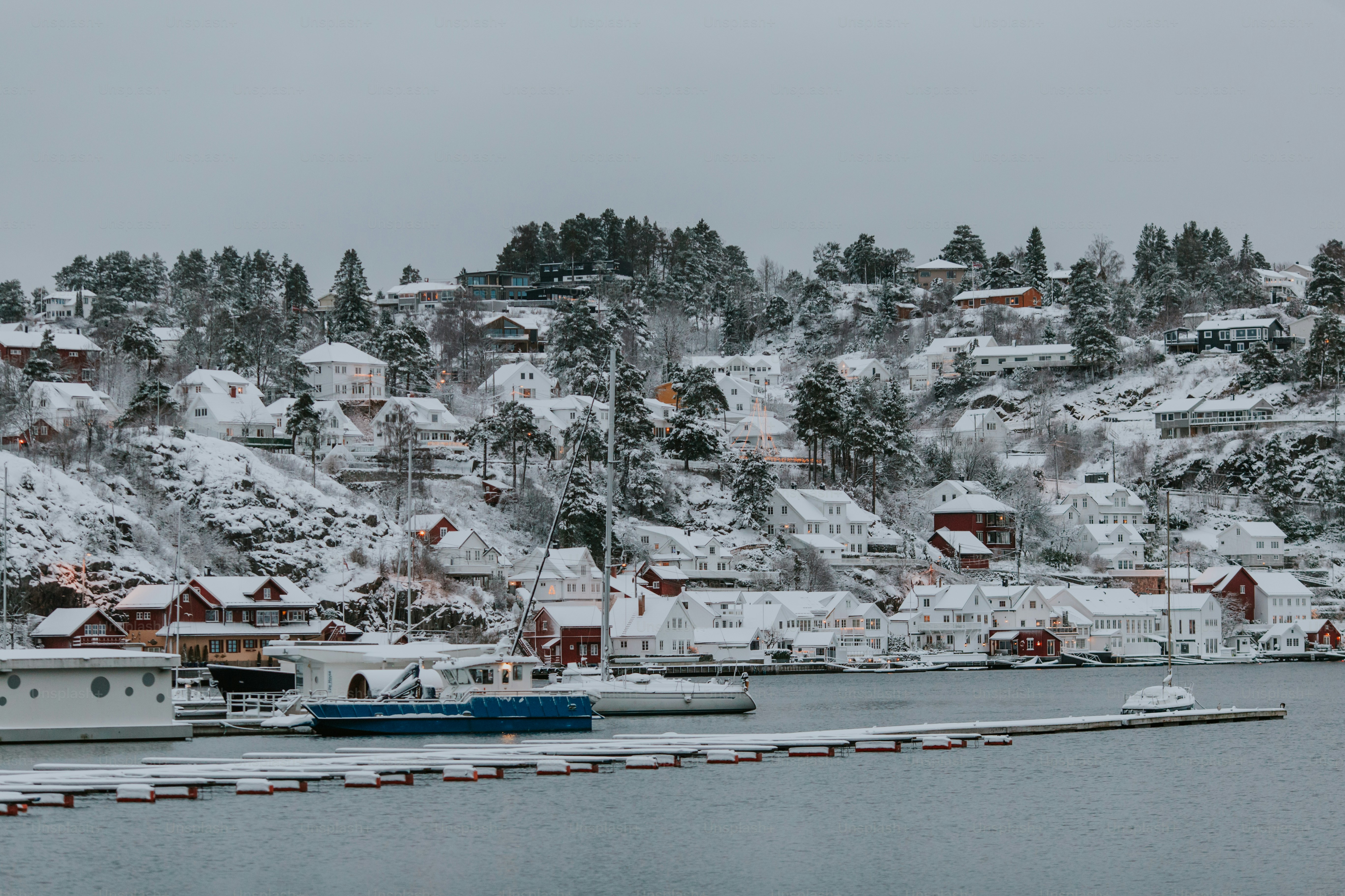 a snow covered mountain with houses and boats in the water