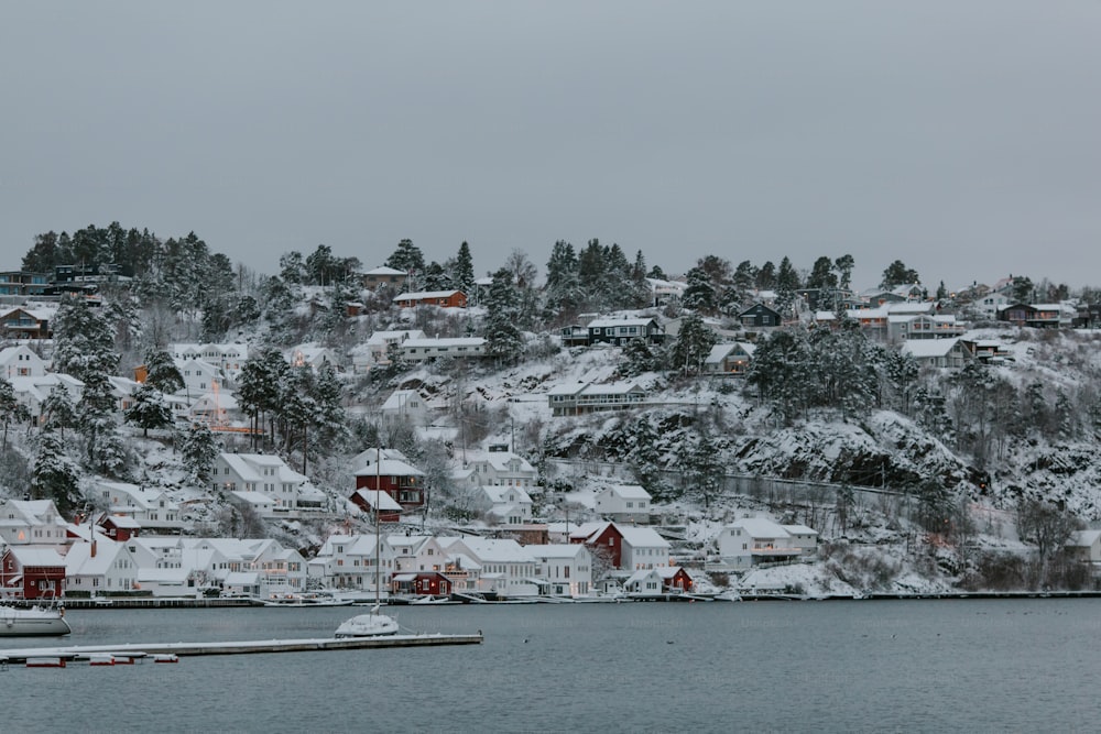 a snow covered hillside with houses and boats in the water