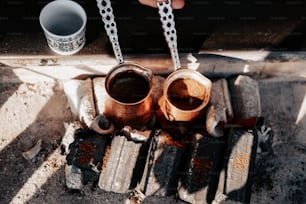 a person holding two mugs over a fire