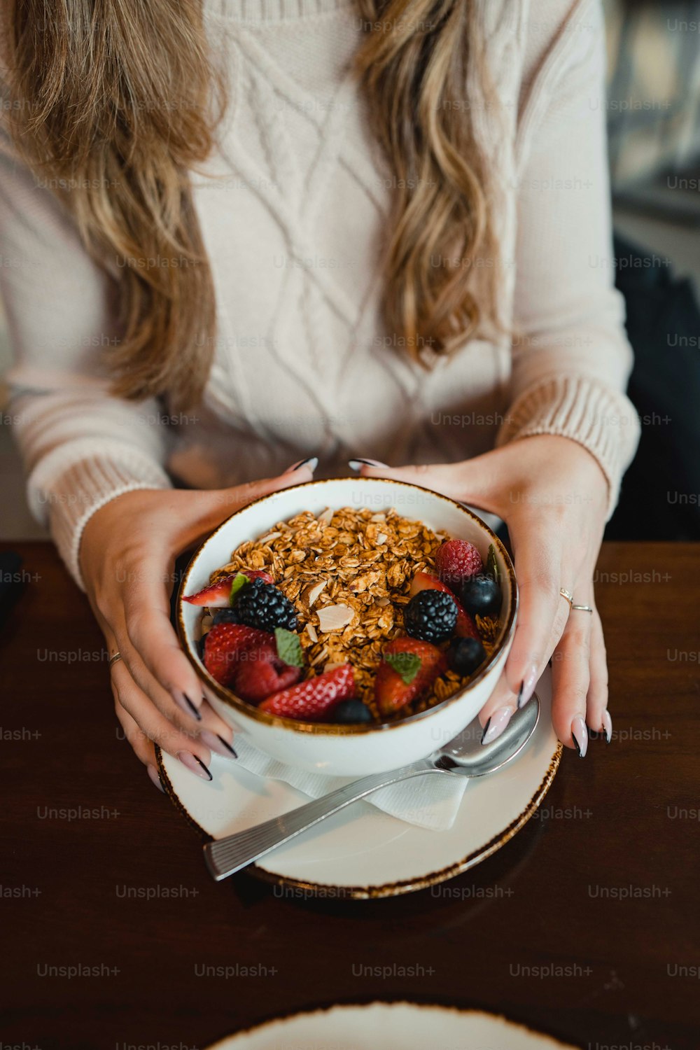 a woman holding a bowl of cereal and berries