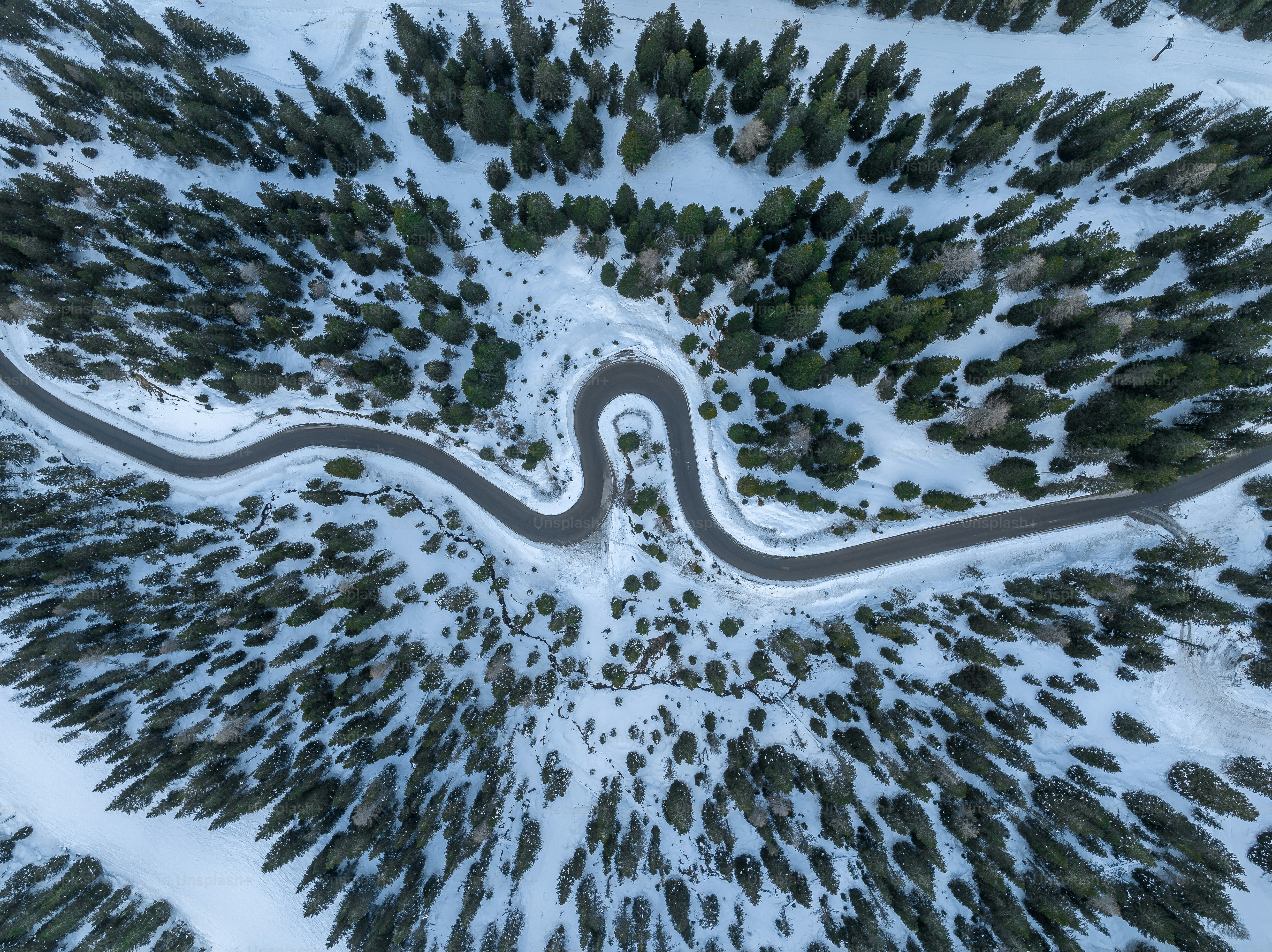 an aerial view of a winding road in the snow