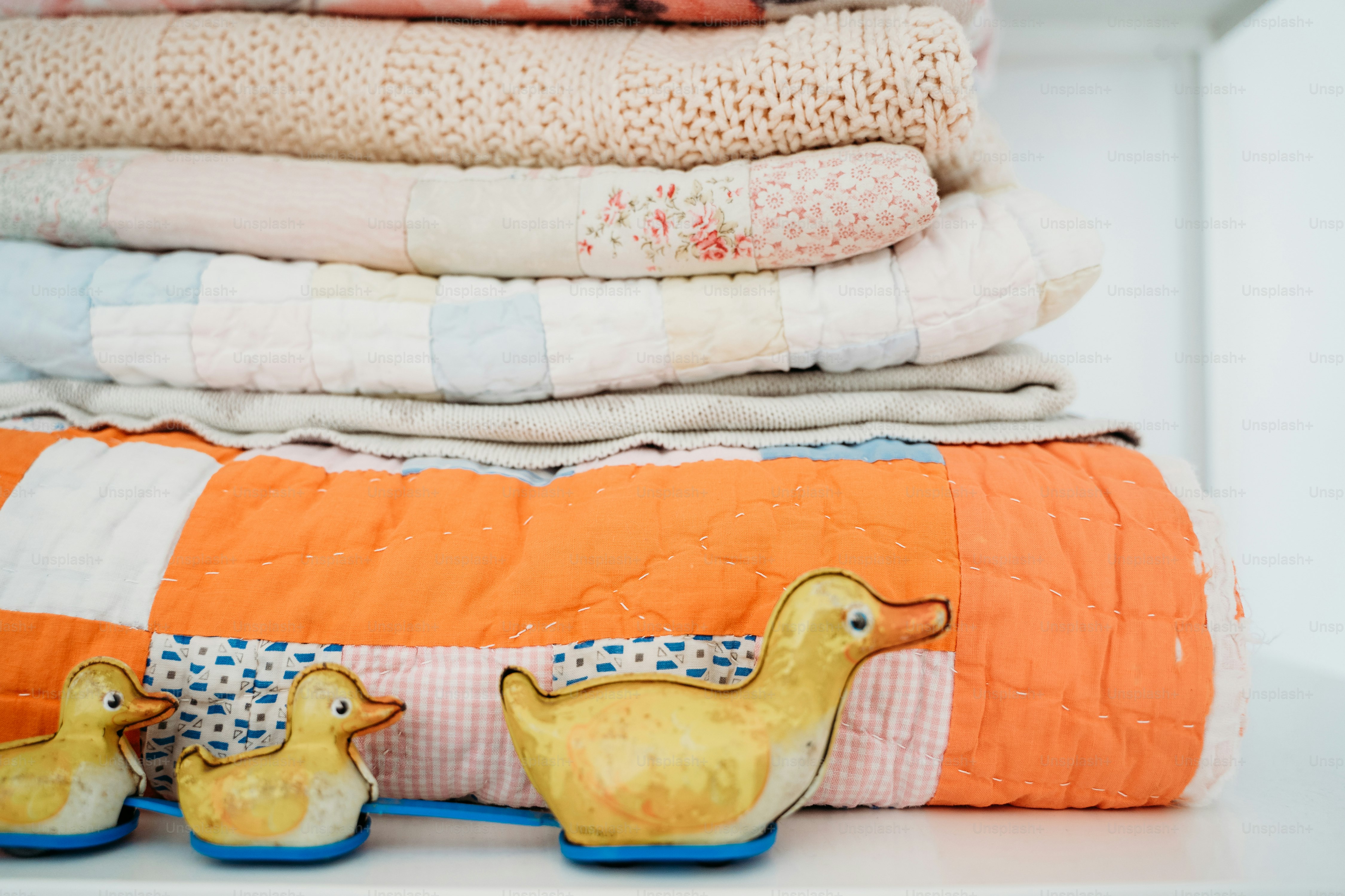 a stack of quilts and rubber ducks on a shelf