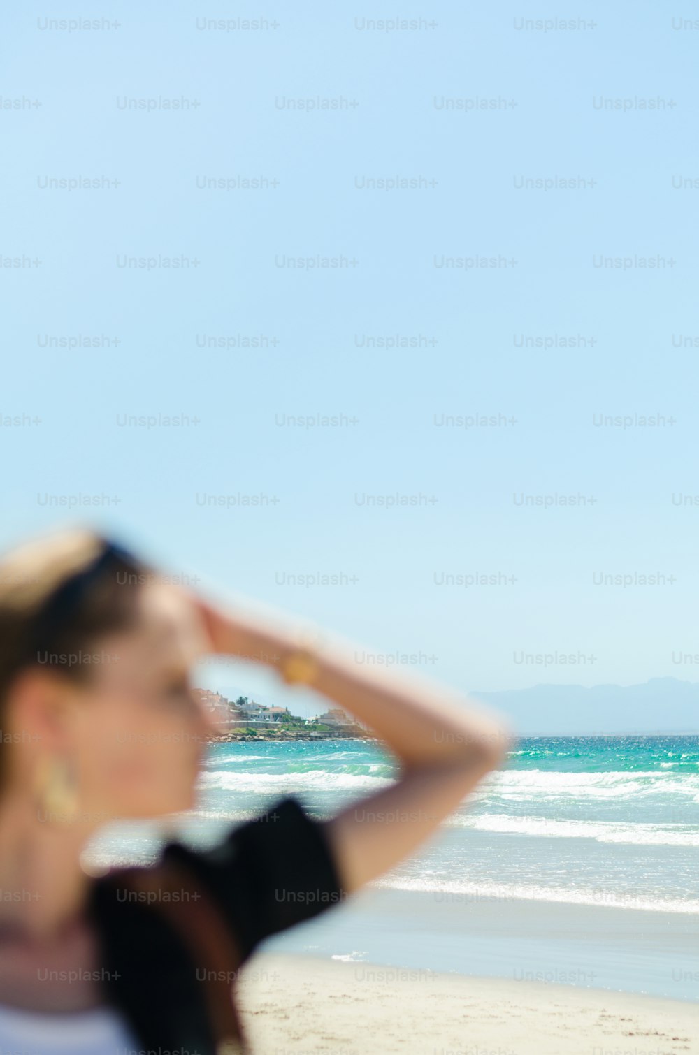 a woman standing on top of a beach next to the ocean