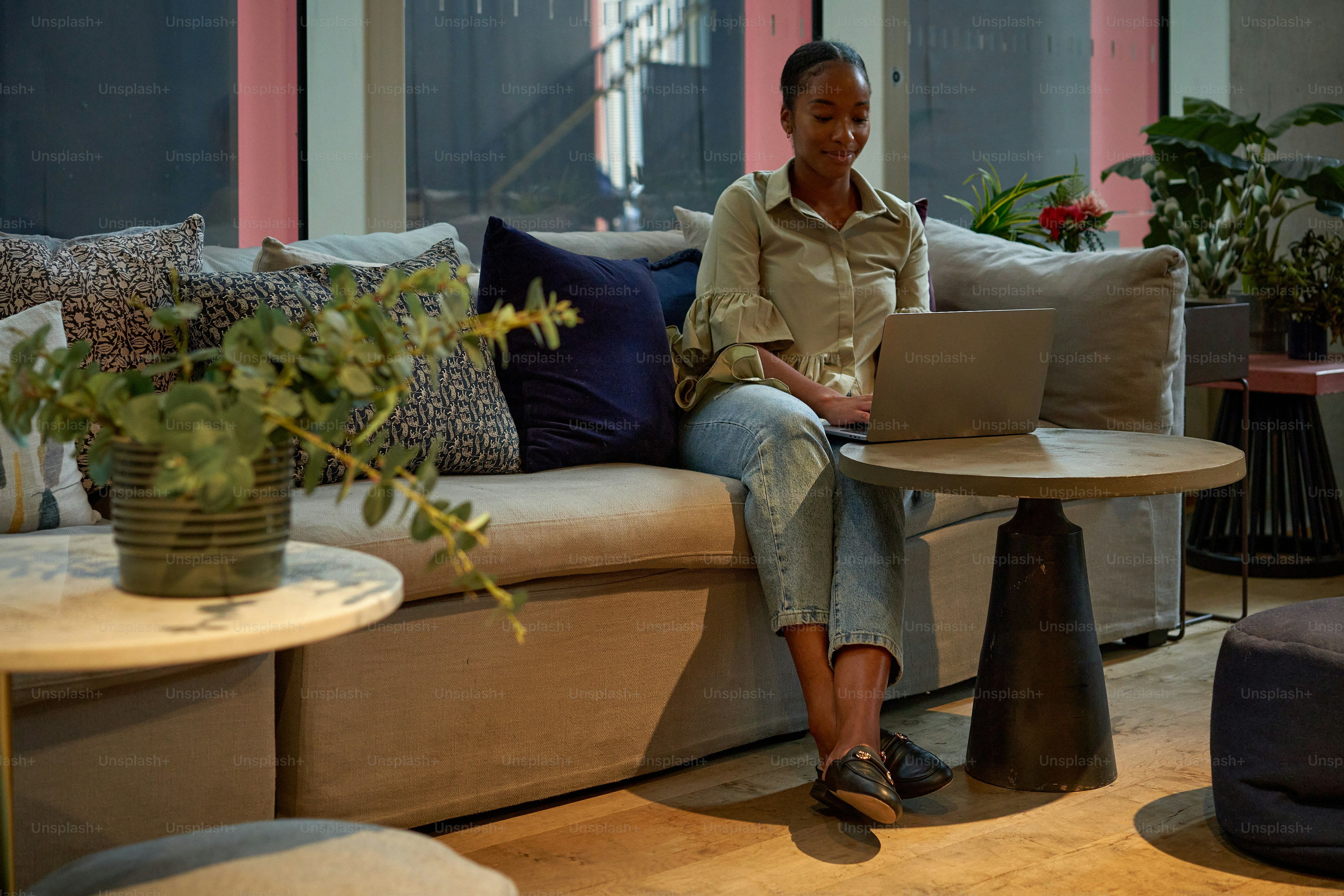 Una mujer sentada en un sofá usando una computadora portátil
